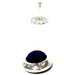 A George V silver hatpin stand, the split sewing stand stop on a blue velvet cushion on a silvered b