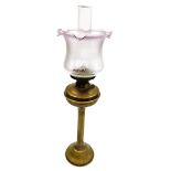 An early 20thC brass oil lamp, with a pink glass shade and reservoir, approx 58cm high overall.