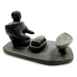 An Inuit soapstone figure group, with figure seated before a bowl, with turret, 10cm high, 17cm wide