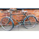 A Goldline Super Atlas gentlemans bicycle, on green metal frame, with bell and bicycle lamp, on a Br