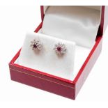 A pair of diamond and ruby set cluster earrings, the central ruby in a raised claw setting, surround