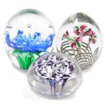 Three paperweights, each of floral decoration, the blue flower 12cm high, the pink and green five st