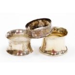 Three silver napkin rings, one of engine turned decoration, on flared rim with vacant cartouche, ano