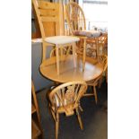 A pine effect circular kitchen table and set of associated four chairs, with wheel back