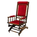 A late 19thC American style walnut rocking chair, with a red velvet padded back, arm rest and