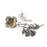 Three floral brooches, to include a marcasite lily brooch, stamped silver, a four leaf flower brooch