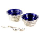 A pair of Victorian silver salts, with blue glass liners, cast with scrolls, leaves, etc.,