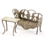 A Dutch white metal miniature settee, decorated with cherubs playing musical instruments, dog,