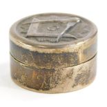 A silver white metal pill box, the hinged lid decorated with Masonic motifs to include angle,