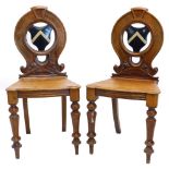 A pair of Victorian oak hall chairs, each with a pierced shield shape back, carved and painted