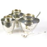 An Elizabeth II Art Deco style silver condiment set, comprising pepper pot, 6cm high, and two lidded