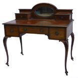 An Edwardian mahogany desk, the raised back with a central oval bevelled mirror plate, flanked by