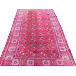 A Kashmir Bokhara design carpet, with a design of medallions on a red ground, one wide border, 300cm
