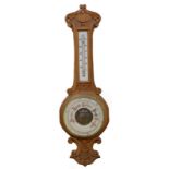 A late 19th/early 20thC carved oak aneroid barometer, in a banjo shaped case, 81cm long overall.