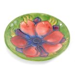 A Moorcroft pottery pin tray, decorated centrally with an anemone flower, on a green ground, 12cm