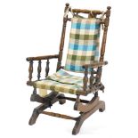 A late 19thC American type walnut child's rocking chair, upholstered in check fabric on sprung end