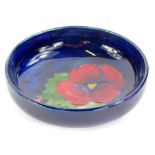 A Moorcroft pottery shallow bowl, decorated with a pansy, on a blue ground, 11.5cm diameter.