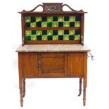 An Edwardian walnut washstand, the raised back inset with Art Nouveau style tiles in green, pink and