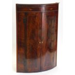 An early 19thC mahogany boxwood strung and marquetry bow fronted corner cabinet, with an inlaid