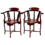 A pair of Chinese hardwood corner chairs, each with a carved and pierced splat, solid seat on shaped