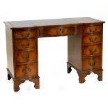 A mahogany kneehole desk, the top with a serpentine front and a green leather insert above nine