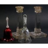 A pair of moulded and gilt glass square section candlesticks, a cranberry tinted bell with