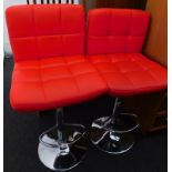A pair of red leatherette and chrome bar stools.