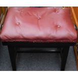 An ebonised piano stool, with red leatherette seat. The upholstery in this lot does not comply