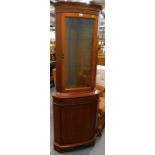 A walnut standing corner cabinet, with glazed door.