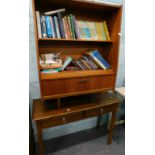 An oak drawer side table and a teak retro bookcase, with some paperback books.