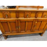 An oak sideboard, with three drawers and three panelled doors, on part-turned supports.