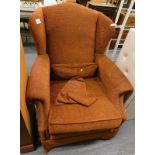 A wingback armchair, upholstered in red and gold patterned fabric. The upholstery in this lot does