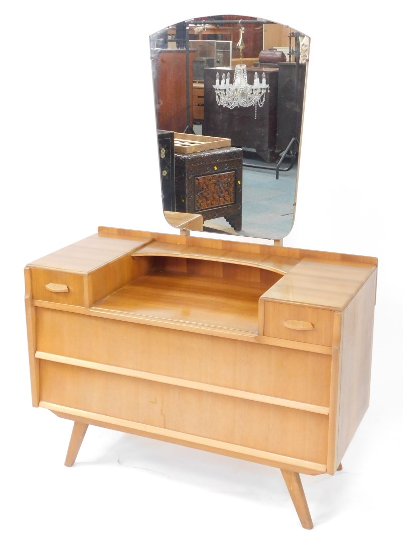 A 1950's vintage walnut dressing chest, possibly by Alfred Cox, the shield shaped mirror above a sha