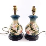 A pair of Moorcroft pottery table lamps decorated with flowers, of baluster form, against a cream to
