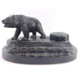 A Black Forest late 19thC desk stand, carved with a bear and a tree stump hinge lidded inkwell, on a