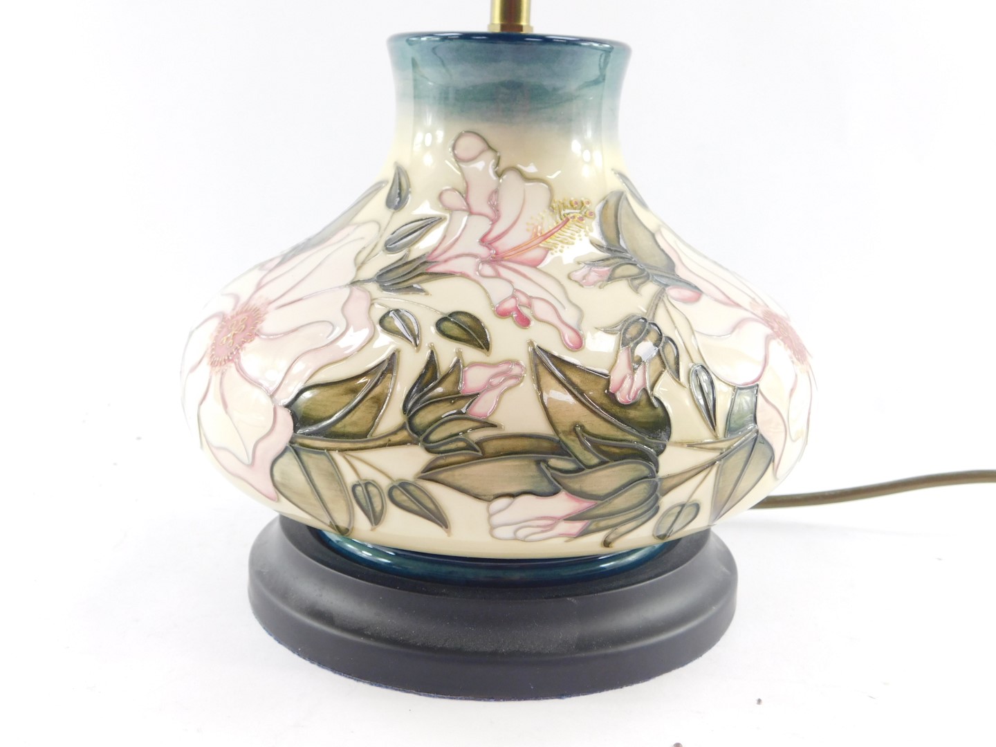 A Moorcroft pottery table lamp decorated in a floral pattern, of baluster form against a cream to bl