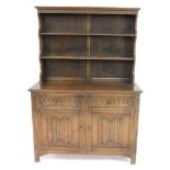 An oak dresser, the out swept pediment above a two shelf plate rack, over two frieze drawers above l