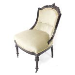 A Victorian ebonised nursing chair, with a foliate carved crest rail, green overstuffed seat and but