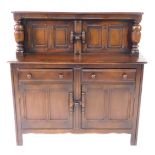 An Ercol dark elm court cupboard, the top with two doors united by a joint latch, raised on cup and