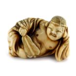 A Japanese Meiji period ivory netsuke of the reclining Buddha, unsigned, 40mm wide.