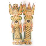 A pair of Balinese wooden carvings of male and female deities, modelled in standing pose, 97cm high.