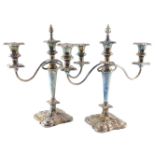 A pair of silver plated three branch candelabrum, with drip pans and extinguishers, 37cm high.