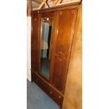 An early 20thC oak and oak veneered wardrobe, with central mirrored door above single drawer,