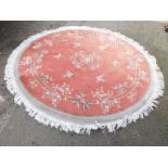 A Chinese circular rug, with red ground decorated with prunus blossom and bamboo.