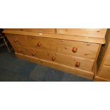 A waxed pine low chest, of three over two drawers, 58cm high, 141cm wide, 53cm deep.