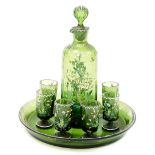 A Continental enamelled green glass liquor decanter and six glasses, on a circular tray, 20cm diamet