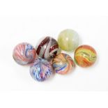 Six various late 19th/early 20thC glass marbles, each with a swirl decoration, some in blue, yellow,