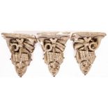 Three antique plaster wall brackets, each with design of trumpets, pan pipes and masks, 48cm high. (