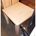 A modern beech effect kitchen table, the extending square top on four tapering legs in a pale overal