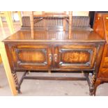 An oak Old Charm console table, the high shield carved back, above two cupboard doors on barleytwist